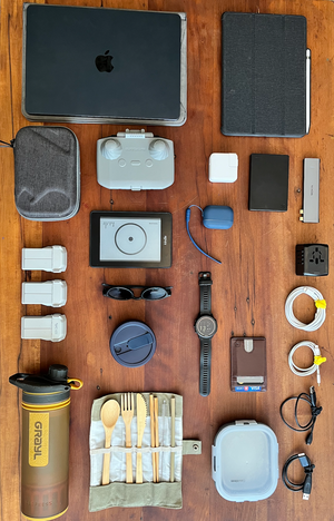 Flatlay of remote work essentials including laptop, camera, drone, and chargers