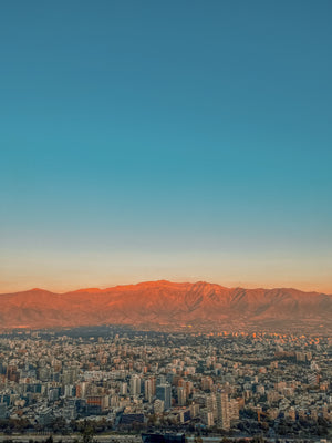 Digital nomads travelling the world. Itinerary of Chile based on couple travel, slow travel, working remotely, vegan travel, and budget travel. Picture of the Santiago, Chile skyline with Andes Mountains in the background.