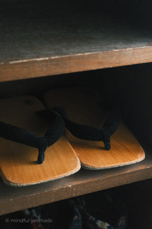Pair of black sandals on wooden slippers on a dark surface