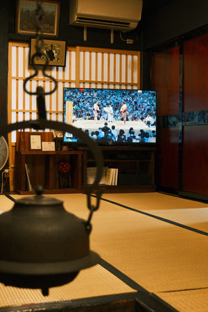 Traditional Japanese room with a TV displaying a sports event.