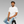 Man sitting on a stool wearing a white t-shirt with small mindful yesmads logo and light blue jeans against a gray background