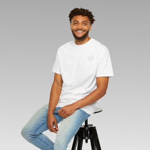 Man sitting on a stool wearing a white t-shirt with small mindful yesmads logo and light blue jeans against a gray background