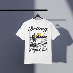 White t-shirt with 'Getting High Club' hiking graphic design on a hanger against a gray background