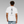 Person wearing a white t-shirt with black Japanese writing (ichi-go ichi-e) text on the back against a gray background