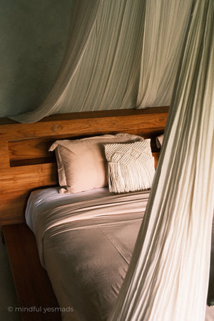 Bed with wooden headboard and draped fabric in a cozy room.