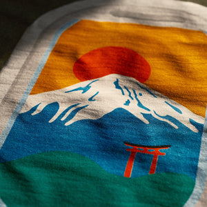 Close-up of a t-shirt with a colorful Mount Fuji and Otorii design from airplane window.