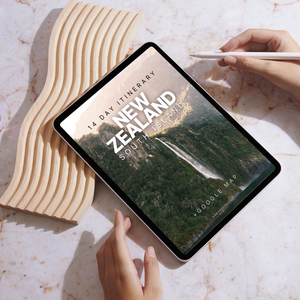 Tablet displaying a New Zealand itinerary on a marble surface with hands interacting.