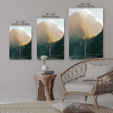 Three mountain landscape paintings of different sizes on a wall above a sofa.