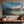 Large canvas print of a mountain landscape hanging on a wall above a wooden shelf with potted plants. Features Mount Cook / Aoraki and nearby lakes in New Zealand.