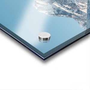 Metallic object on a reflective surface with water and sky in the background. Features Mount Cook / Aoraki and nearby lakes in New Zealand.