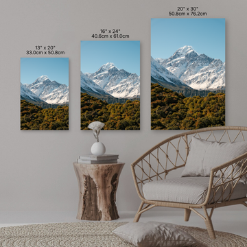 Three mountain landscape wall art prints on a wall with a sofa and side table.