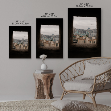 Three framed artworks of cityscapes on a wall with a sofa and side table in the foreground.