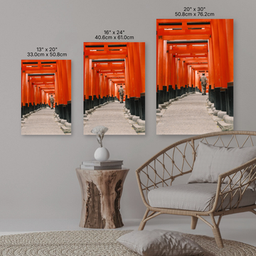 Three sizes of a red torii gate artwork displayed on a wall with a sofa and side table.