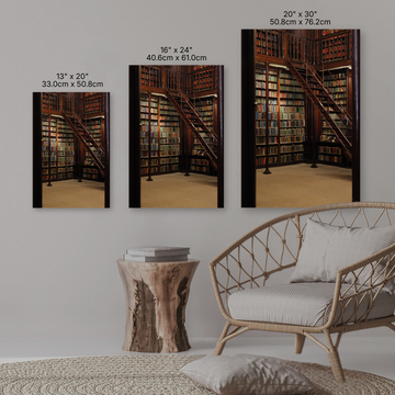 Three wall art prints of a library scene with corresponding sizes displayed above, in a room with a wicker chair and wooden table.