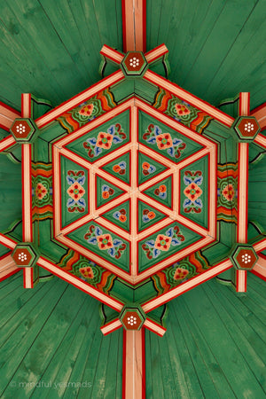 Decorative ceiling with geometric pattern in red, green, and multicolor on a green background. featuring Dancheong geometric patterns in Seoul, South Korea.