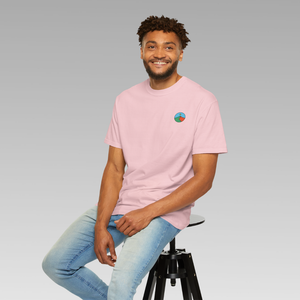 Man wearing a pink t-shirt with Mindful Yesmads logo, sitting on a stool against a gray background