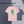 Pink t-shirt with a graphic New Zealand mountains, campervan, and sheep design on a hanger against a dark background